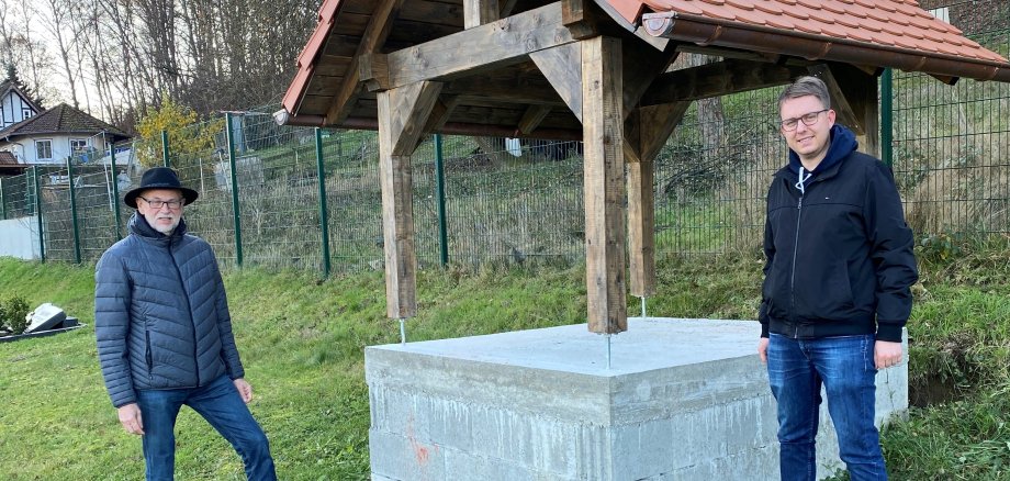 Das Foto zeigt Ortsvorsteher Otmar Müller und Maximilian Kröll von der Friedhofsverwaltung der Stadt Wächtersbach am Glockenturm im Hesseldorfer Friedhof.