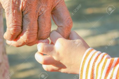 Seniorenhand und Kleinkindhand halten aneinander fest